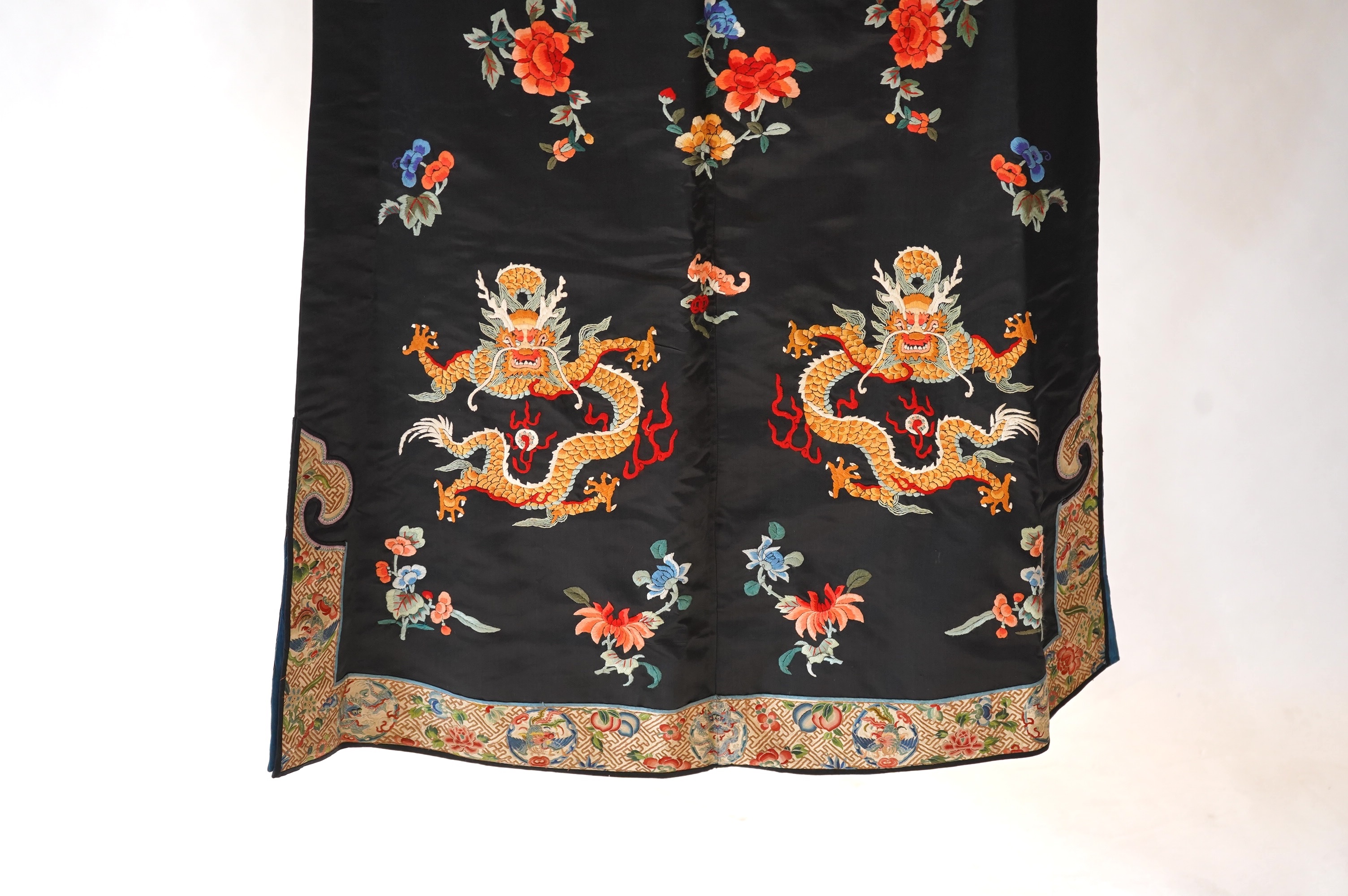 An early 20th century Chinese blue satin silk embroidered dragon robe, embroidered with five claw dragon symbols with flaming pearls, surrounded by bats and flower motifs, with gold thread embroidered dragon sleeve bands